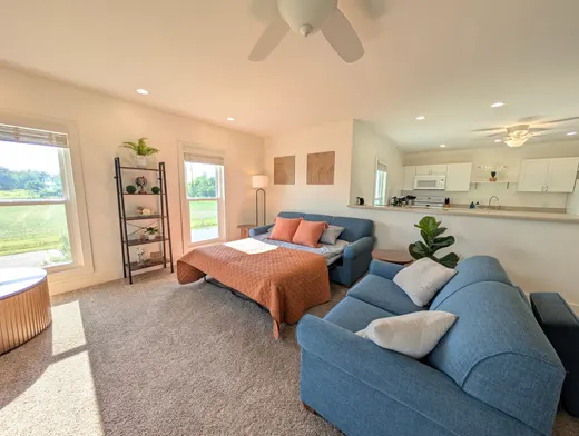 Upstairs living area with a blue queen sofa bed made up with orange bedding.