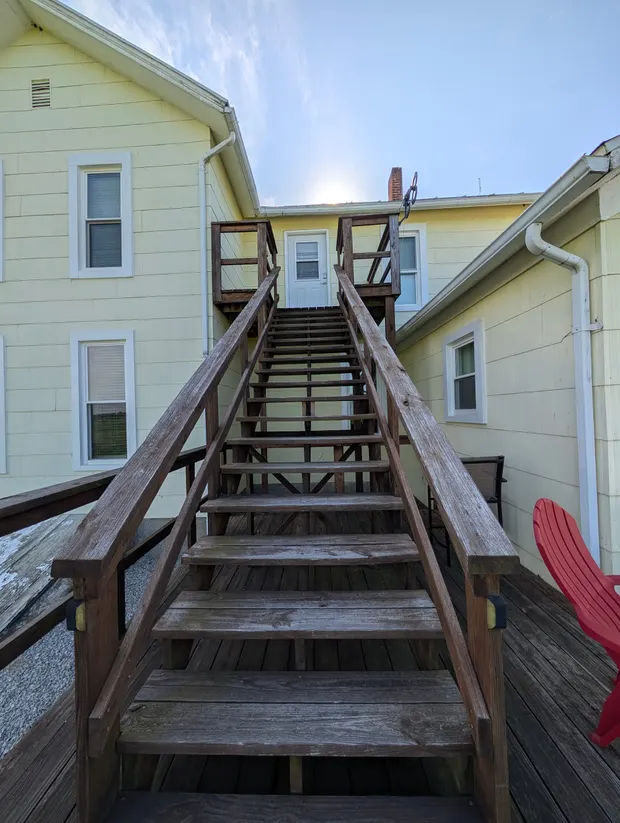 Wooden exterior staircase leading up to the upstairs apartment door.